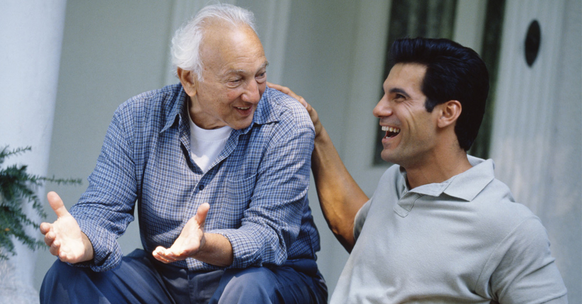 Health Benefits of Laughter. Picture of an elderly Caucasian man laughing with a young Caucasian man.