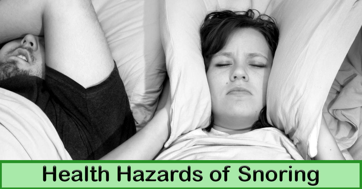Health Hazards of Snoring. Picture of a caucasian male and female laying in bed, he is sleeping and she is holding a pillow around her ears to block out his snoring.